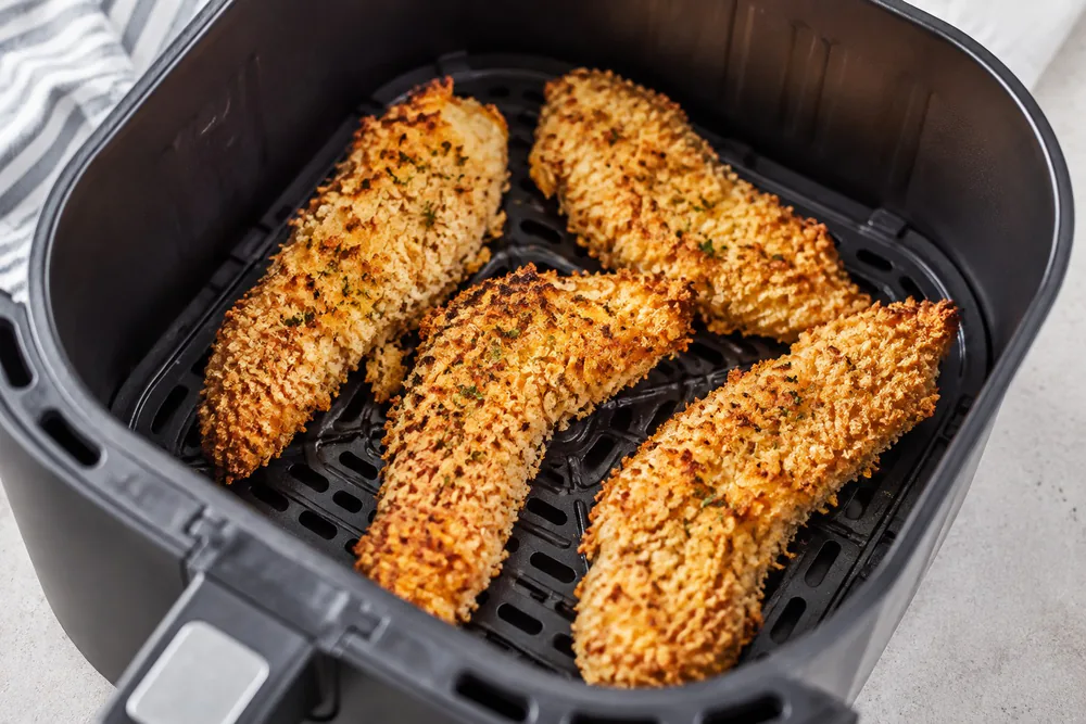 Panko-crusted chicken tenders in an air fryer basket.