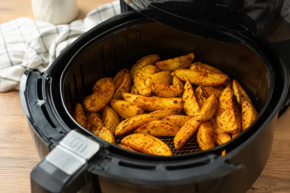 Golden potato wedges with paprika in an air fryer basket.