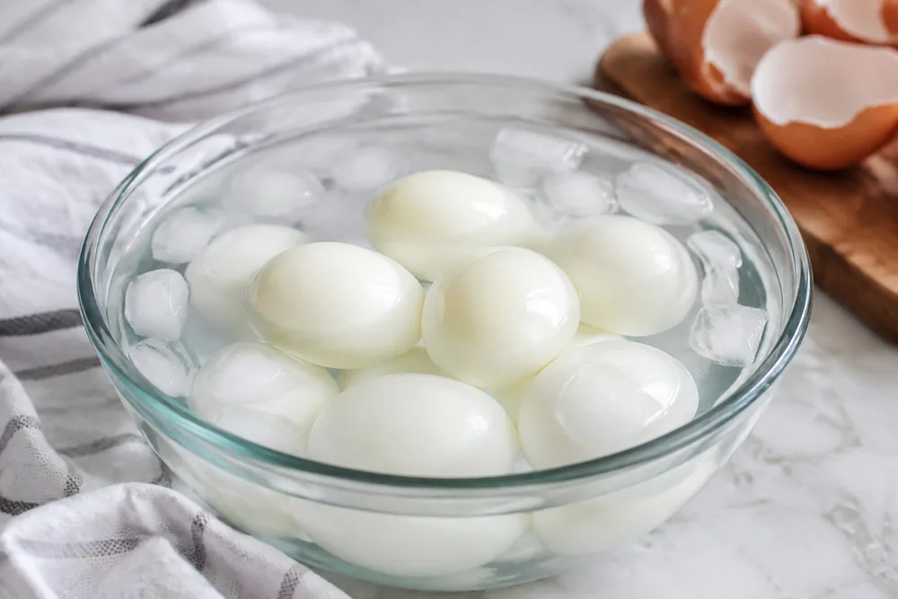 Peeled hard-boiled eggs in a bowl after an ice bath.