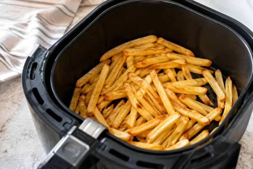 Golden frozen french fries in an air fryer basket.