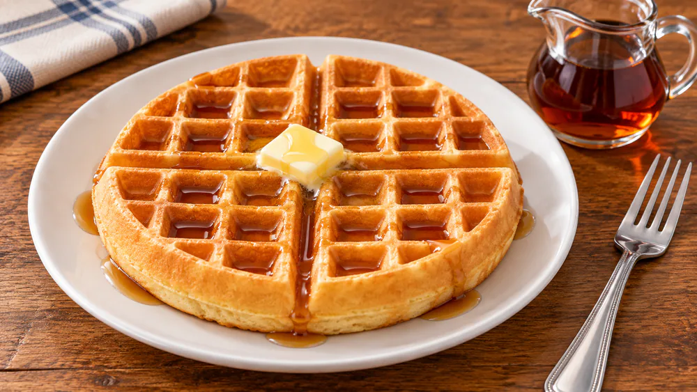 A tall golden brown Belgian waffle from the Presto FlipSide on a plate, deep pockets filled with syrup and butter