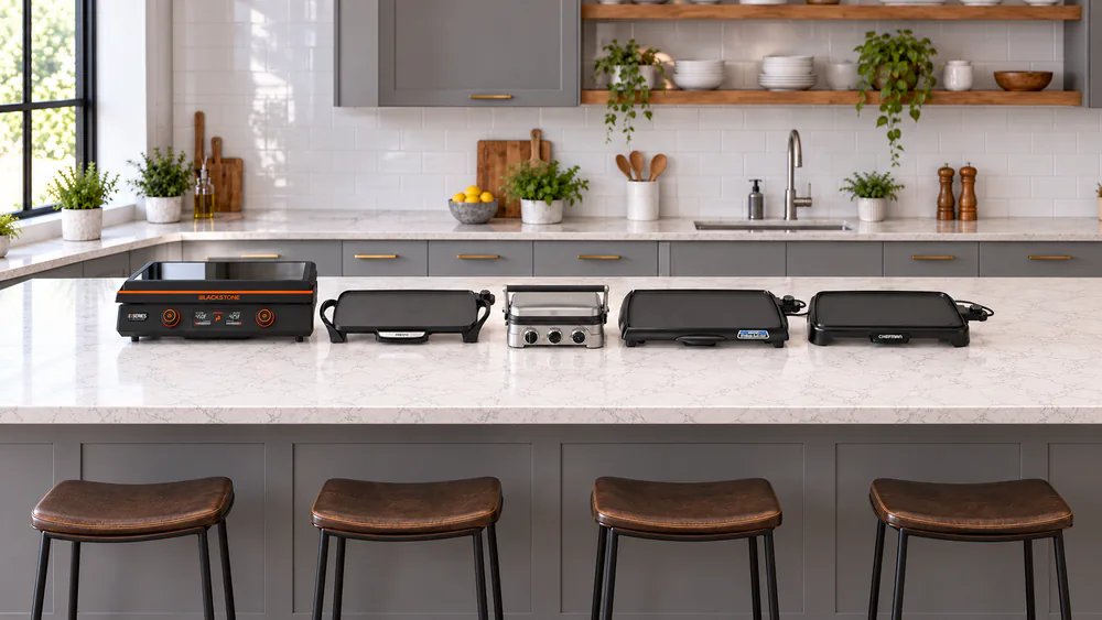 Five countertop electric griddles of different sizes lined up on a kitchen counter, including a Blackstone E-Series with its glass hood and a Presto with removable handles