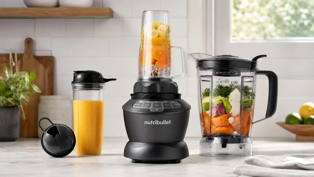 The NutriBullet Full-Size Combo with its 64-oz pitcher and the 32-oz and 24-oz single-serve cups arranged around the 1200W base on a kitchen counter.