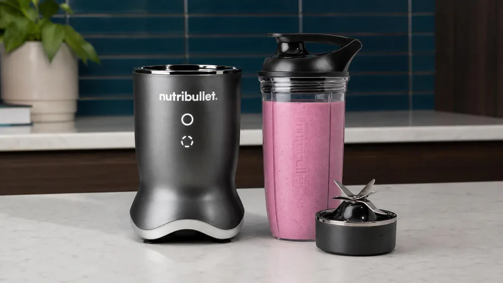 A NutriBullet Ultra with its 32-oz cup full of a creamy frozen berry shake, the titanium-coated blade assembly resting on the counter beside it.