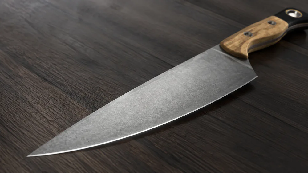 Macro shot of the Benchmade Chef Knife's 14-degree SelectEdge bevel along the edge line, reflecting a bright strip of light.