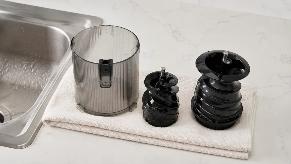 The Hurom H400 chamber and two-part auger laid out on a counter after rinsing, with no strainer mesh in the parts lineup.