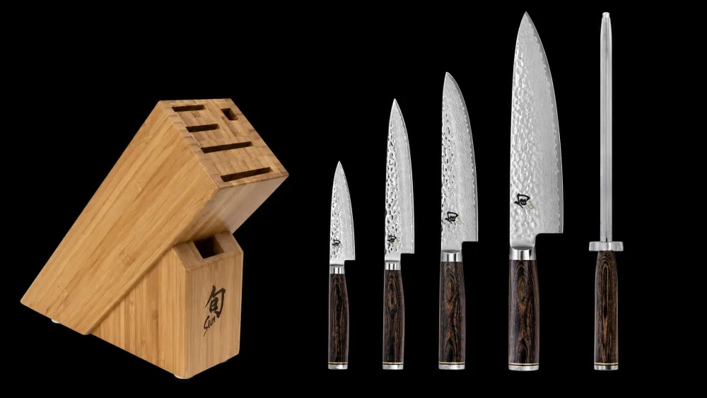 A forged German chef's knife and a Japanese santoku side by side on a cutting board.