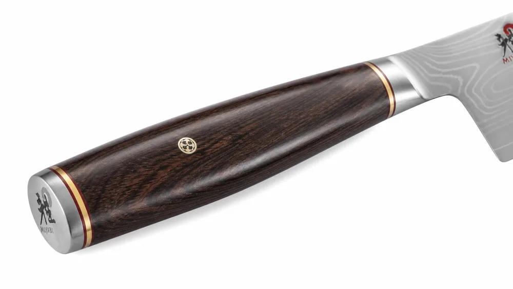 Close-up of the Miyabi Artisan D-shaped Pakkawood handle with brass spacers on a santoku.