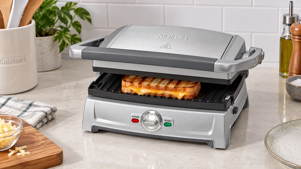 A Cuisinart Griddler Compact pressing a grilled sandwich on a small apartment kitchen counter