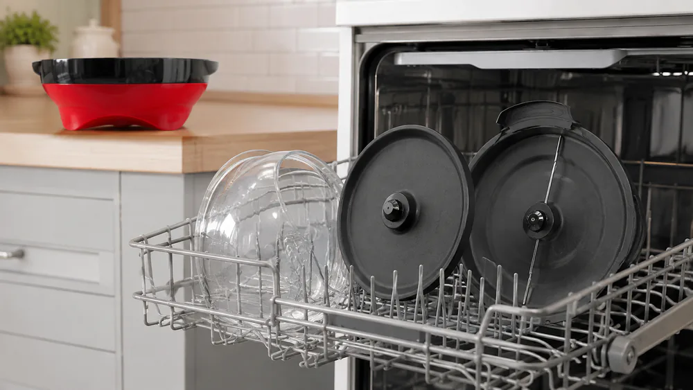 A TLGREEN 6-quart popper with its plate and stir tray removed and standing in a dishwasher rack, the base wiped clean beside it.