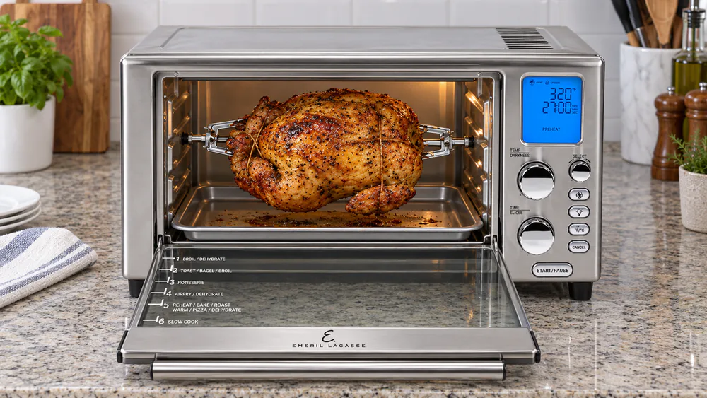A finished rotisserie chicken on the spit inside the Emeril Power AirFryer 360 XL, skin browned and crisp.