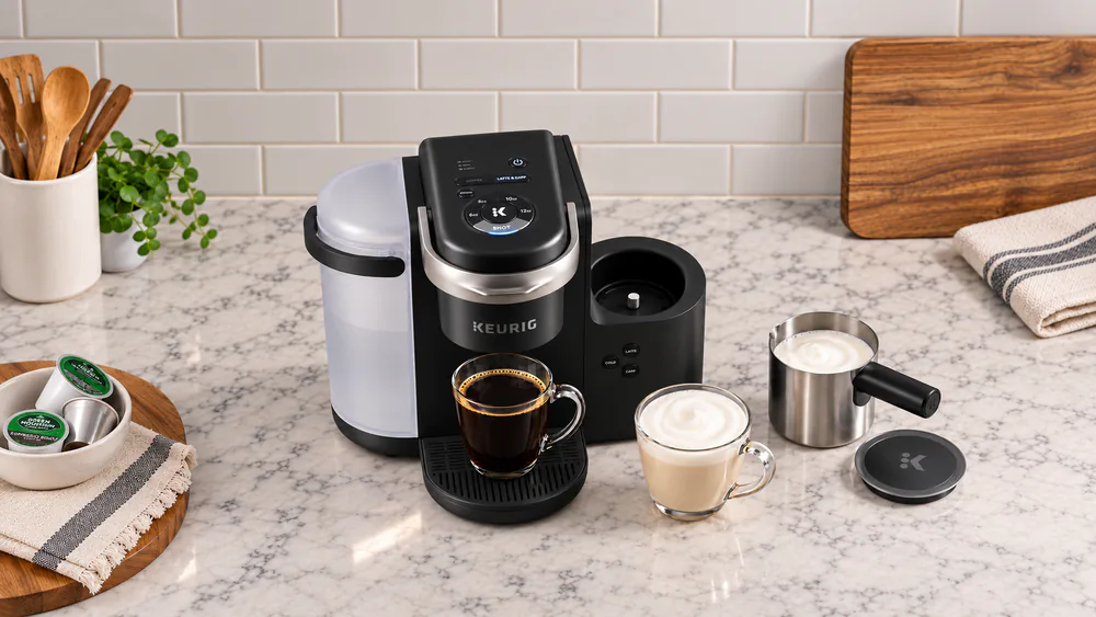 Keurig K-Cafe with a mug of frothed milk beside the removable frother and the SHOT button lit on the top control panel