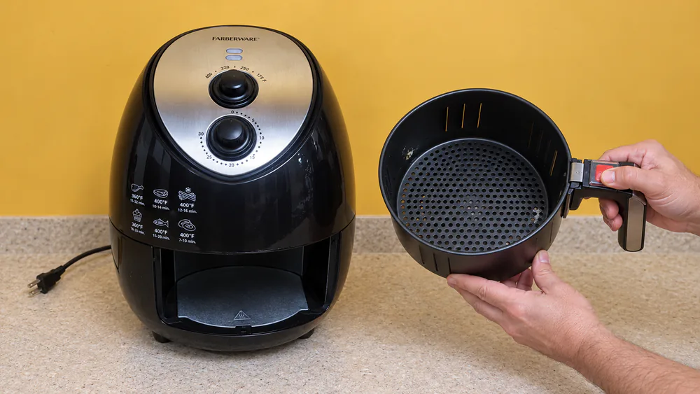 Close-up of a Farberware air fryer nonstick basket with light wear on the coating, held under a kitchen light for inspection
