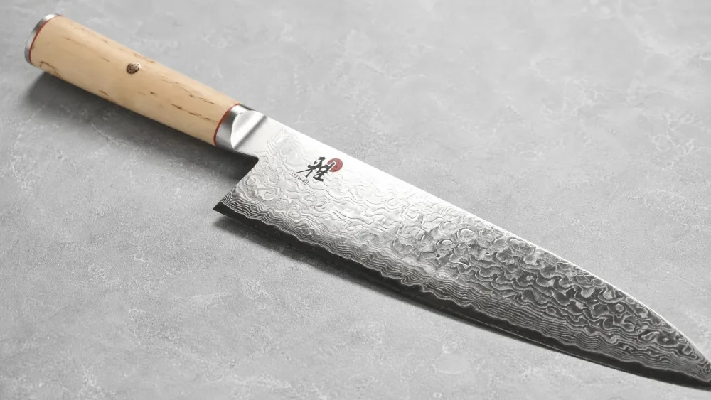 The Miyabi Birchwood SG2 gyuto with its 100-layer flower Damascus pattern and light Karelian birch handle.