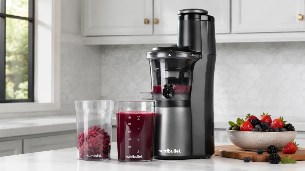 A NutriBullet Slow Juicer NBJ50300 pressing berries, no-drip container of juice in front.