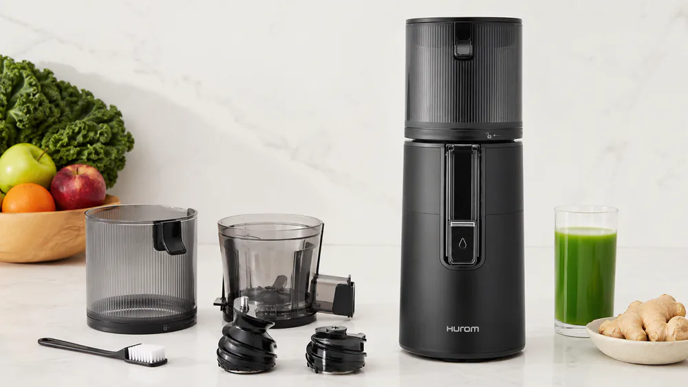 The Hurom H400's two-part auger disassembled on a counter, showing the strainer-free chamber with no mesh screen to scrub.