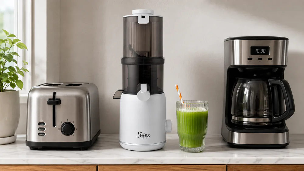 The Tribest Shine compact cold press juicer on a narrow counter between a toaster and a coffee maker, showing its small footprint.