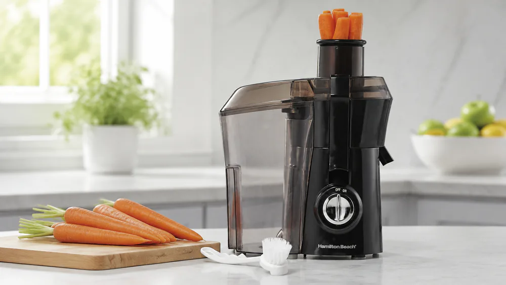 The Hamilton Beach 67601A Big Mouth juicer on a counter with a handful of carrots ready to drop into its 3-inch chute.