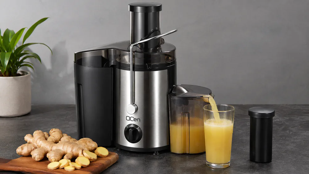 The QCen 500W centrifugal juicer filling a glass with foamy ginger juice in under 30 seconds