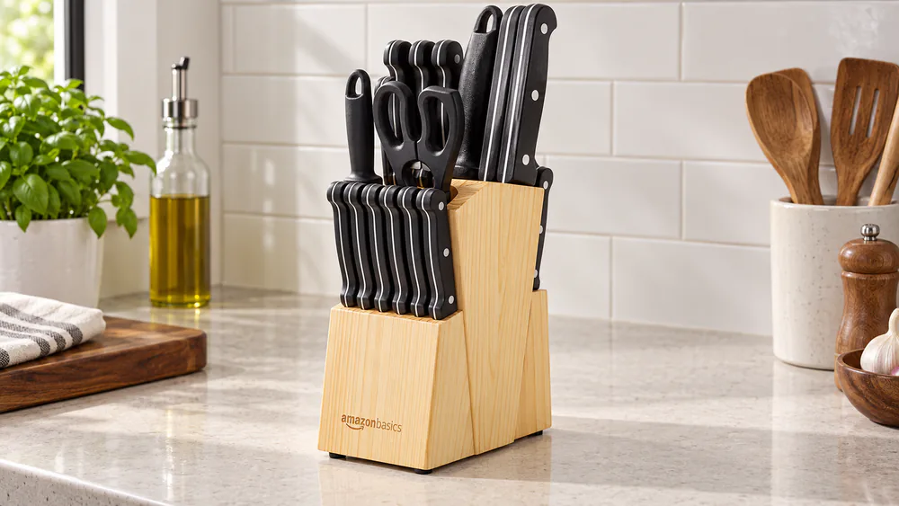 The Amazon Basics 14-piece set in its pinewood block on a small counter, chef's knife and slicing knife in the front slots.