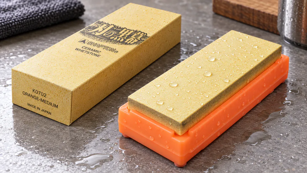 A Shapton Pro 1000 whetstone in its plastic case, water beading on the stone surface.