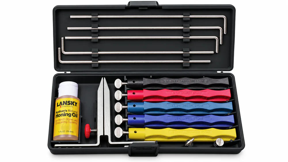 The Lansky Deluxe 5-Stone system laid out with its five color-coded hones, guide rods, and flip-over clamp in the molded case.