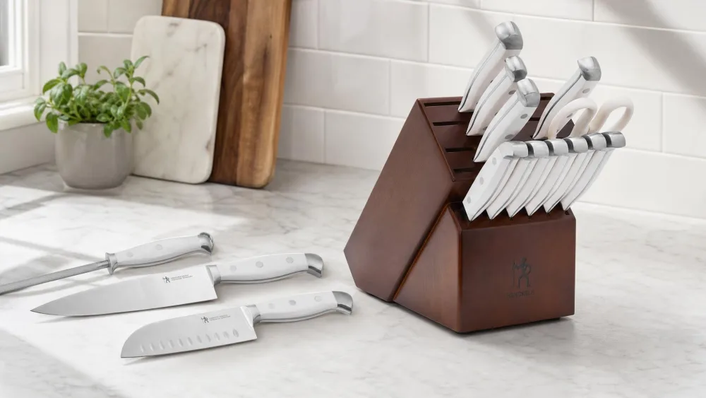 The Henckels Statement wooden knife block on a kitchen counter with the chef's knife, santoku and honing steel lifted out and laid alongside.