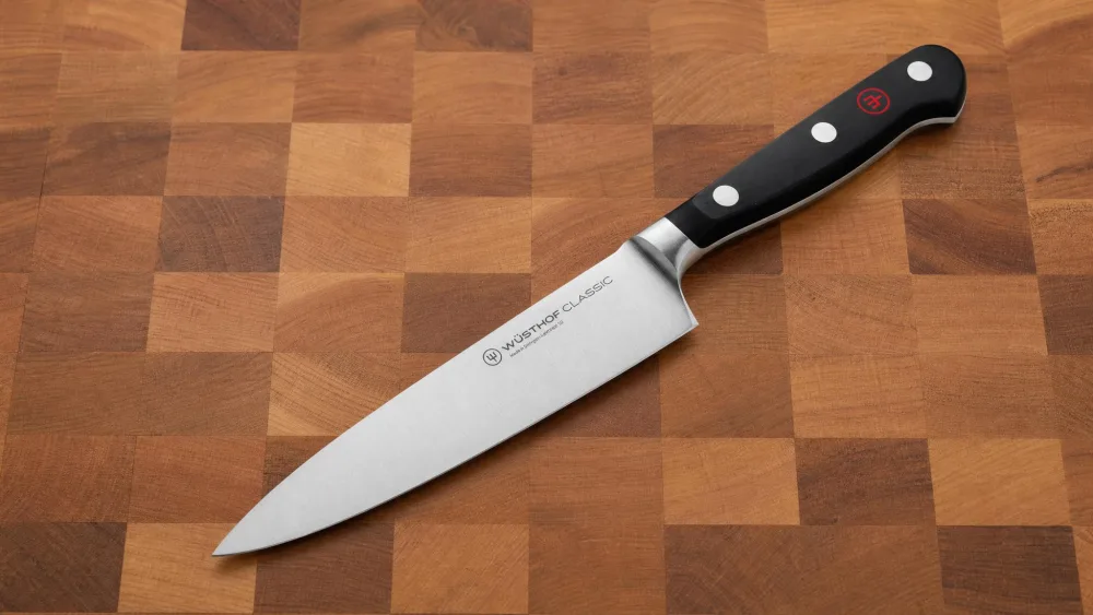 A Wusthof Classic 8-inch chef's knife resting on a butcher block, photographed to show the full bolster and finger guard where the blade meets the handle.