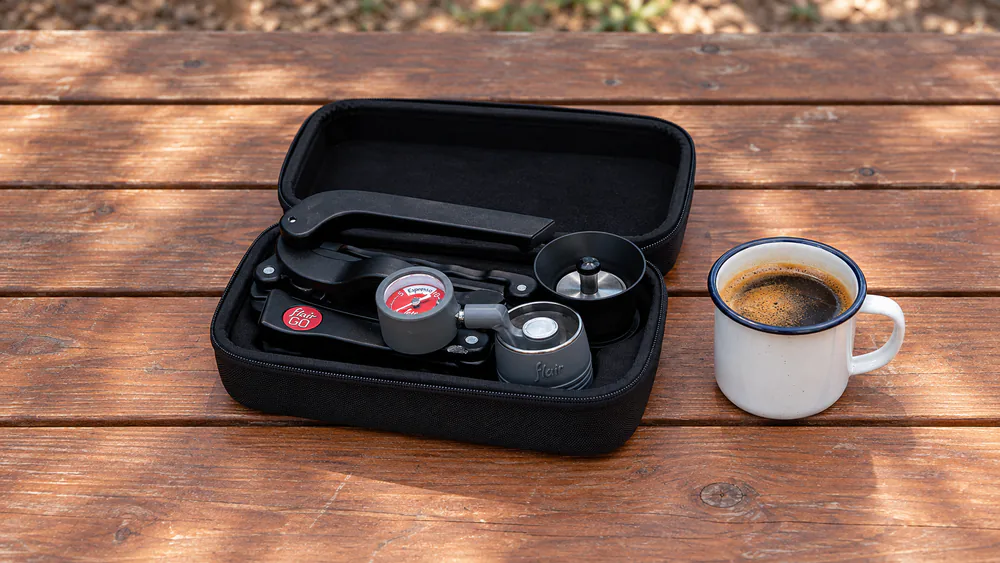 Flair 2GO folded flat inside its molded carrying case next to a camp mug