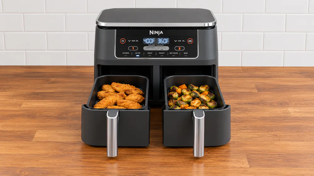 Ninja Foodi DZ201 DualZone air fryer on a kitchen counter with both 4 qt baskets open, chicken tenders in one and roasted vegetables in the other