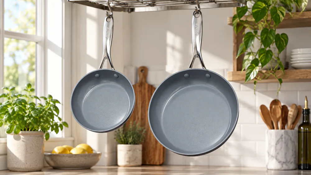 The GreenPan Valencia Pro 8-inch and 10-inch pans hanging on a pot rack, dark bodies with mirror-polished handles.
