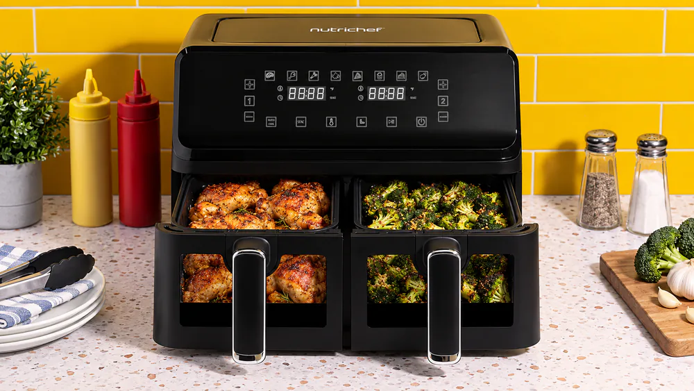Both baskets of a NutriChef 8.8 quart double basket air fryer pulled open, one holding chicken thighs and the other roasted broccoli