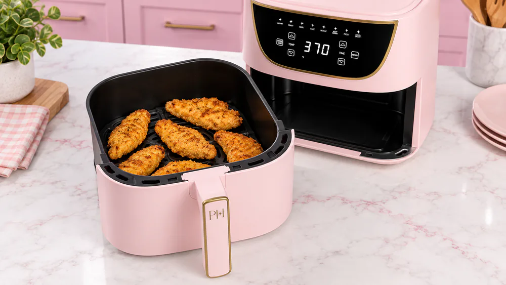 Open basket of the Paris Hilton air fryer filled with golden chicken tenders on the crisper plate