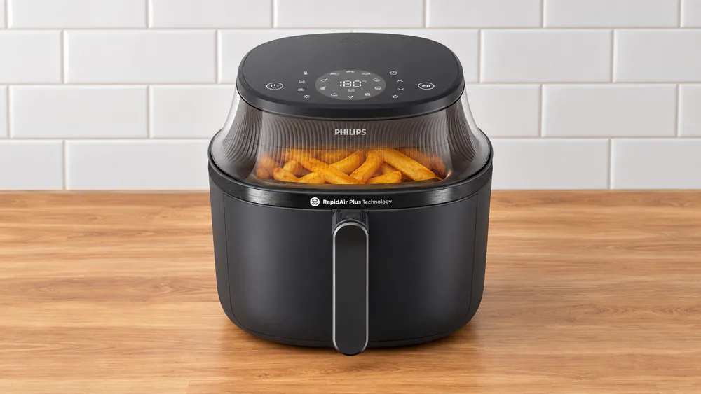 A Philips 3000 Series 6.5 qt air fryer with its front cooking window showing golden fries mid-cook