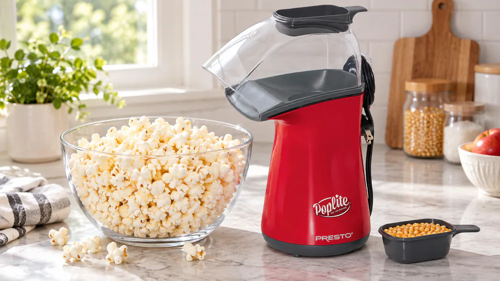 A half-cup cap of kernels beside a bowl of popped corn and the Presto PopLite on a counter.