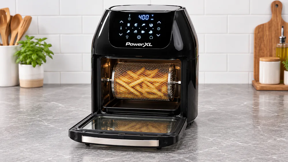 A PowerXL Air Fryer Pro oven with its door open and the rotating mesh basket full of fries.