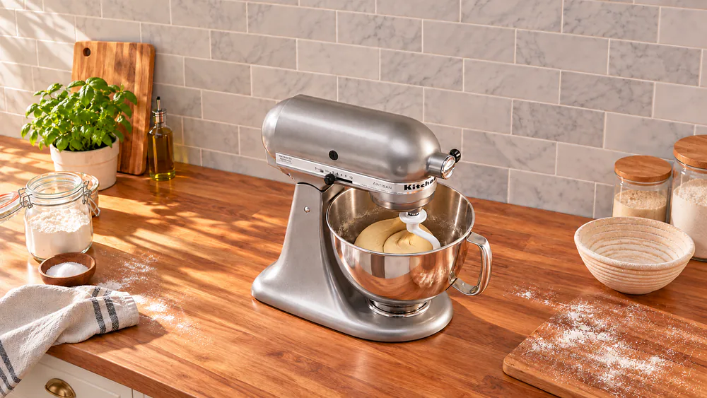 KitchenAid Artisan 5-Qt with its head locked down and a dough hook kneading a smooth ball of bread dough