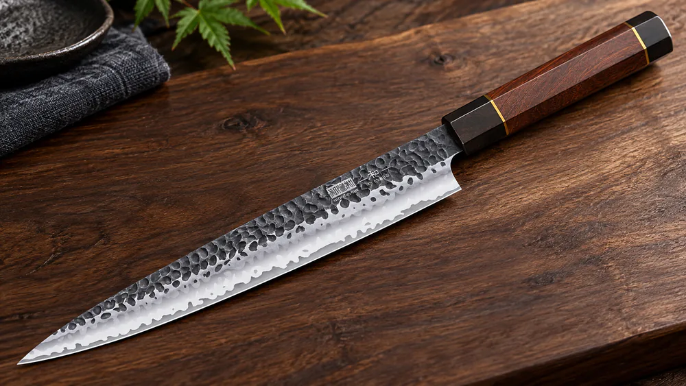 Close-up of a HOSHANHO sushi knife blade showing the layered Damascus pattern and copper-wire rosewood handle.