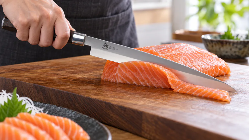 Close-up of a KYOKU Samurai yanagiba slicing raw salmon on a wooden board in one clean stroke.