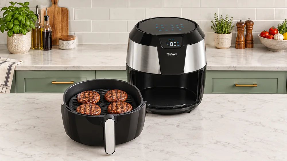 Four burgers with dark grill marks sitting on the cast-aluminum grill plate of a T-fal Easy Fry XXL air fryer and grill