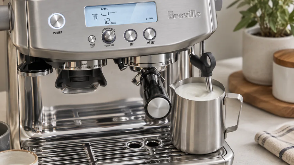 The Barista Pro's steam wand texturing milk in a stainless pitcher, silky microfoam building on the surface.