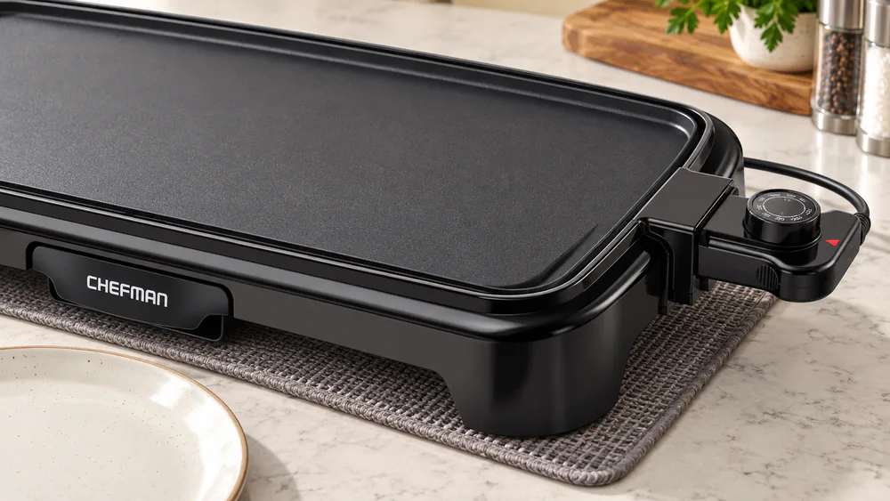 Close-up of the Chefman electric griddle's plastic legs and removable temperature control on a kitchen counter