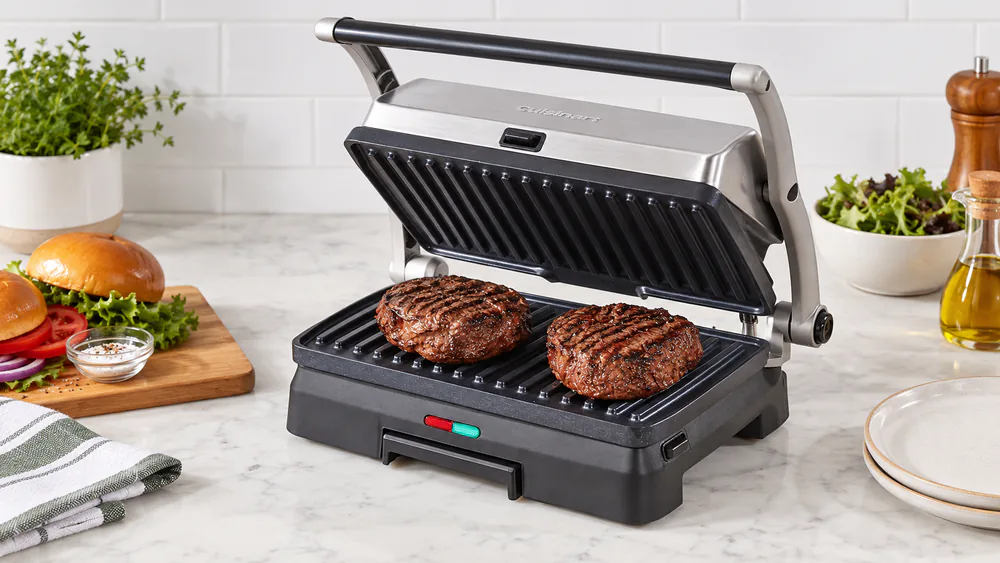 Cuisinart Griddler GR-11NAS with its lid open showing two burger patties with dark grill marks on the ceramic plate