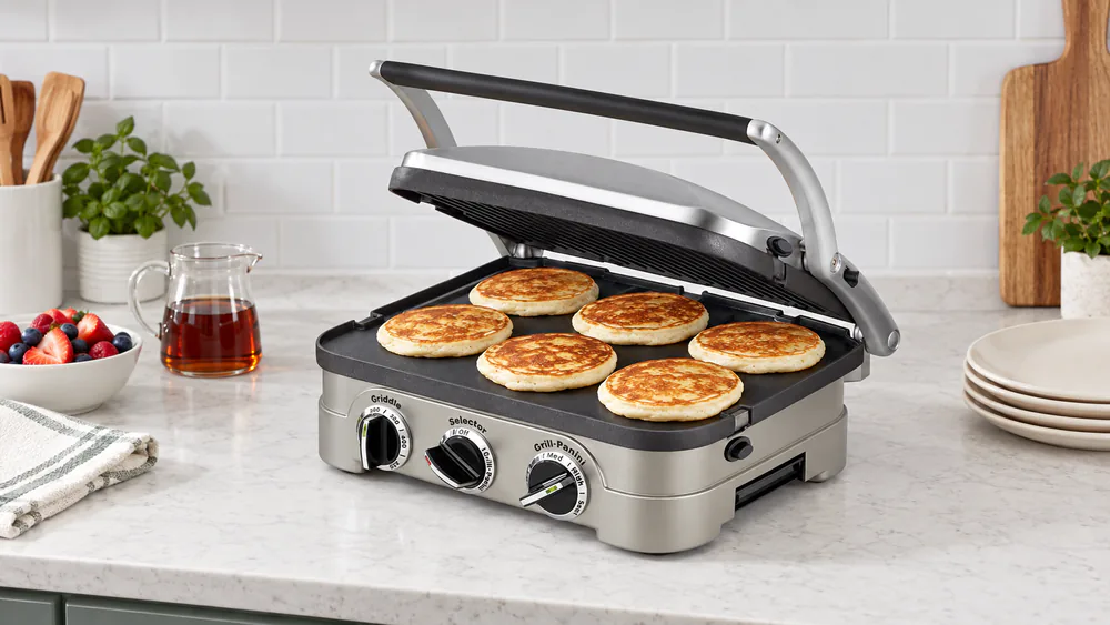 Golden pancakes cooking evenly across the flat nonstick griddle plate of the Cuisinart Griddler 5-in-1