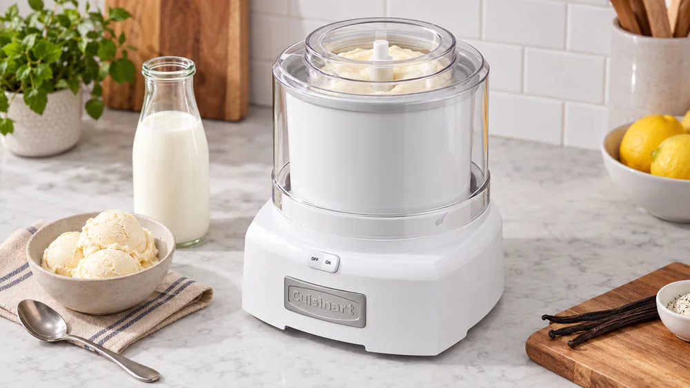 A Cuisinart ICE-21 with its transparent lid on, mixing paddle turning fresh vanilla ice cream to soft-serve consistency inside the frozen bowl.