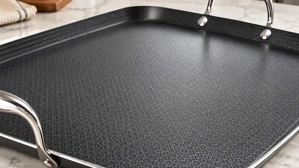 Close-up of the HexClad griddle's laser-etched hexagon surface showing stainless steel peaks and dark ceramic valleys