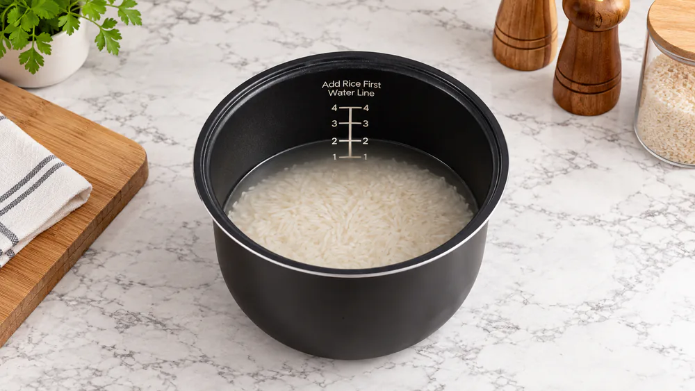 The inside of an Aroma inner pot showing rice covered with water that reaches the number 2 line