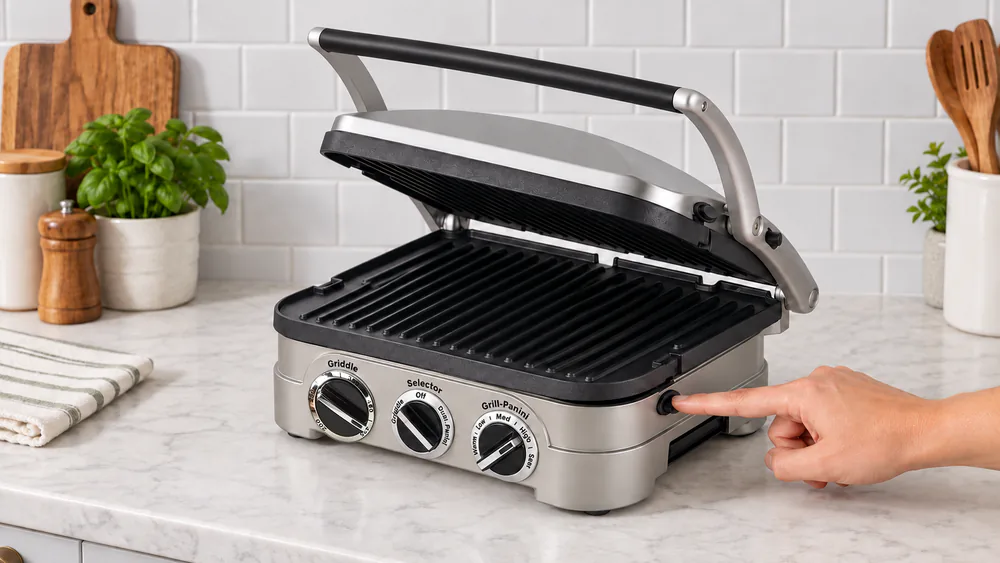 A cool Cuisinart Griddler with the cover open and a hand pressing the plate release button on the right side so the grill plate pops up