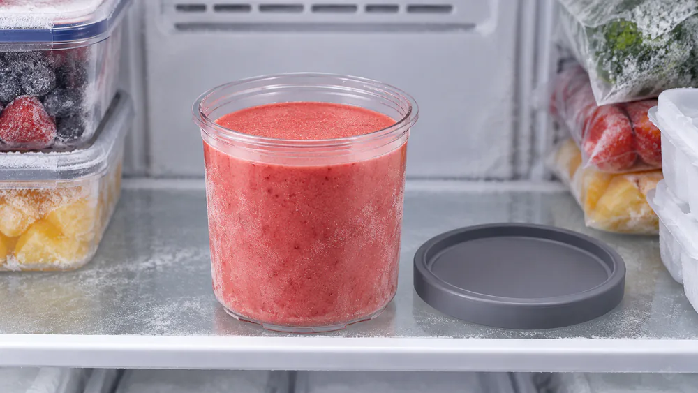 A filled Ninja Creami pint sitting level on a freezer shelf with a flat frozen surface on top.
