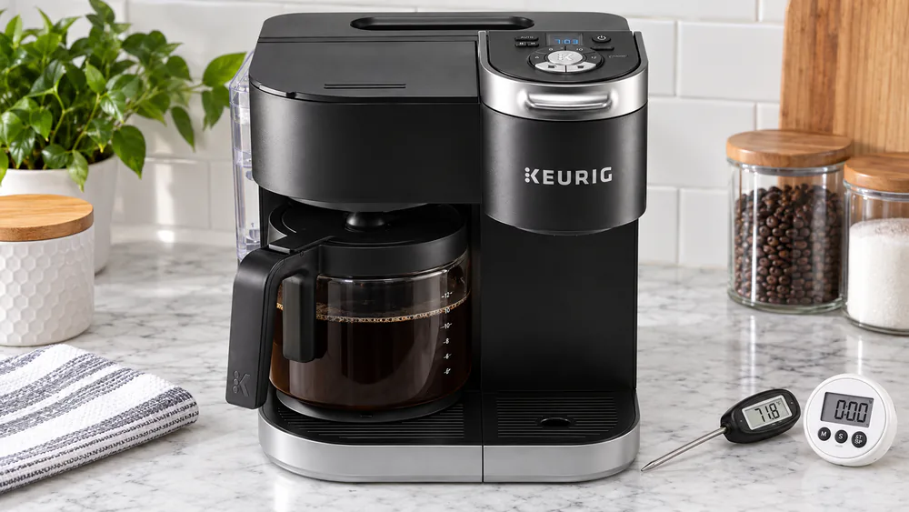 A Keurig K-Duo on a test-kitchen counter beside a digital food thermometer and a timer